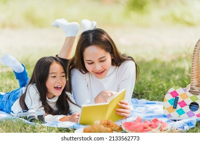 Happy Asian Young Family Mother And Child Little Girl Having Fun And Enjoying Outdoor Laying On Picnic Blanket Reading Book At Summer Garden Spring Park, Family Relaxation Concept