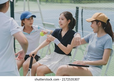 Happy Asian Young Friendship Sitting, Talking And Resting After Match On The Outside Tennis Court. Sport Activity, Tennis Training And Competition Concept.