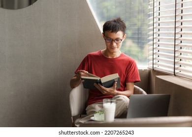 Happy Asian Young Man Reading A Book In Cafe.