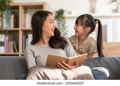 Happy asian young mother smile reading fairy tale story with daughter in living room at home. Little girl enjoy with fairy tale story from mom on couch looking book together.Relaxed time at home - Powered by Shutterstock