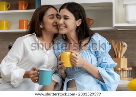Happy Asian young pretty woman and her girlfriend holding coffee mugs and chatting together in kitchen, The moment romantic time of female lover, LGBTQ freedom of love concept, copy space