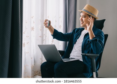 Happy Asian Young Teen Man At Home Holding Phone Looking At Screen Waving Hand Video Calling Distance Friend Online In Mobile Chat App Using Smartphone Videochat Application.