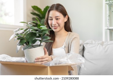 Happy Asian Young Woman, Customer Received, Unpack Package Carton Open Parcel In Cardboard Box, Holding Ceramic Plant Pot. Moving, Preparing In New House, Relocation. Online Shop Delivery At Home.