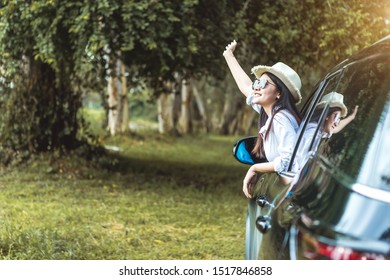 Happy Asian Young Woman Enjoying A Ride In A Car With Hand Greeting. The Concept Of Road Travel And Adventure. 