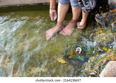 A Happy Asian Young Woman Relaxing In A Hot Spring And Using Her Foot To Bail Out The Water.