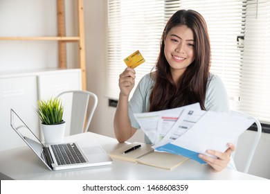 Happy asian young woman smiling holding so many expenses bills such as electricity bill,water bill,internet bill and cell phone bill with easy life to payment credit card on her hand