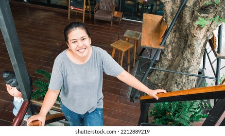 Happy Asian Young Woman Standing In The Coffee Shop. One Female Only Enjoying At The Cafe In The City. Lady Girl While Relaxing Outside The Restaurant.