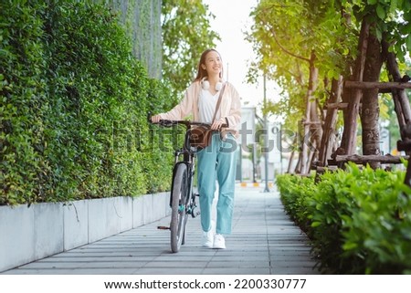 Happy Asian young woman walk and ride bicycle in park, street city her smiling using bike of transportation, ECO friendly, People lifestyle concept.
