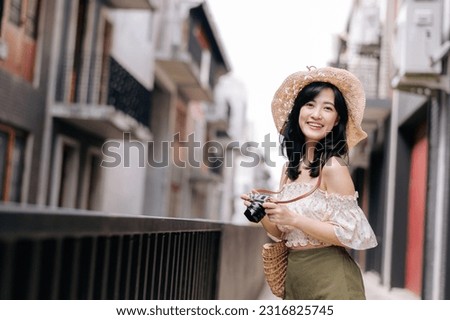 Happy asian youth woman with camera travels street city trip on leisure weekend. Young hipster female tourist sightseeing summer urban Bangkok destination. Asia summer tourism concept.