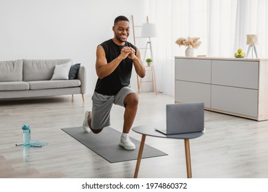 Happy Atheltic African American Man Doing Forward Lunge Exercise Watching Online Workout Video Tutorial Training At Home. Lunges Exercises, Domestic Male Fitness Concept. Selective Focus