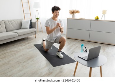 Happy Atheltic Young Asian Man Doing Forward Lunge Exercise Watching Online Workout Video Tutorial Training At Home In Living Room Using Pc. Domestic Male Fitness Concept. Selective Focus