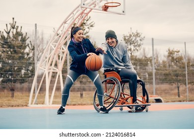 Happy athlete in wheelchair and his female friend having fun while playing basketball outdoors. - Powered by Shutterstock