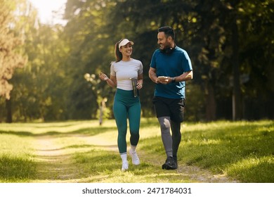 Happy athletic couple communicating while walking in nature after sports training. Copy space.  - Powered by Shutterstock