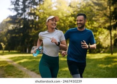 Happy athletic couple having fun while running together in nature. Copy space.