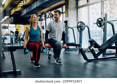 Happy athletic couple having weight training in lunge position at health club. Copy space.