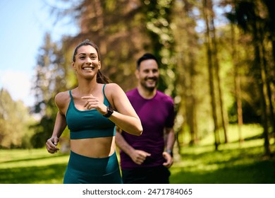 Happy athletic couple jogging while exercising in nature. Focus is on woman.  - Powered by Shutterstock