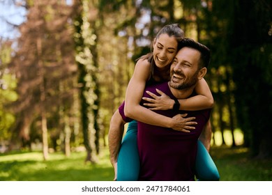 Happy athletic couple in love piggybacking in the park. Copy space. - Powered by Shutterstock