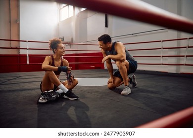 Happy athletic woman communicating with her boxing instructor while having water break in health club. Copy space.  - Powered by Shutterstock