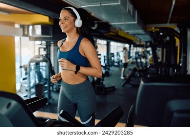 Happy athletic woman exercising on treadmill during sports training in a gym. Copy space. 