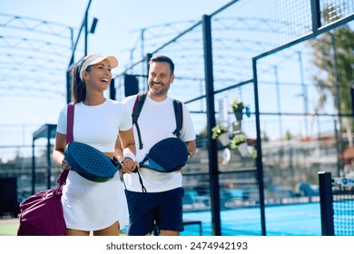 Happy athletic woman and her friend going to play paddle tennis on outdoor court. Copy space.  - Powered by Shutterstock