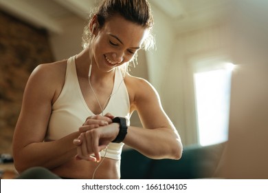 Happy Athletic Woman Measuring Heart Rate On Smart Watch While Resting After Exercising At Home. 