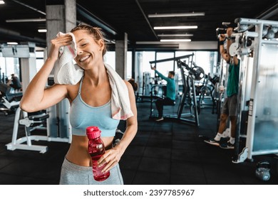 Happy athletic woman taking a break at the gym. Smiling attractive woman feeling tired but proud after successful training session. - Powered by Shutterstock