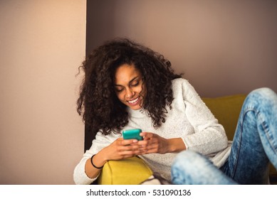 Happy Attractive African American Girl Texting On A Mobile Phone.