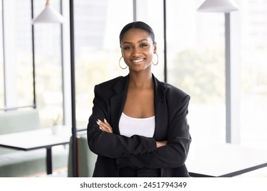 Happy attractive African business leader woman looking at camera with arms folded, smiling, posing in co-working space. Positive lawyer, consultant, manager professional portrait - Powered by Shutterstock