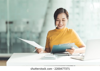 Happy Attractive Asian Business Woman Working With A Laptop And Financial Document At Office, Successful Action, Business Concept.