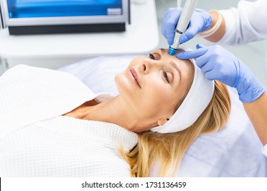 Happy attractive Caucasian woman in a bathrobe enjoying the microdermabrasion treatment in a beauty parlor