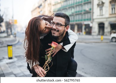 Happy Attractive Couple Enjoying City Outdoors. Piggy Back Ride. People In Love And Valentine's Day Theme. 