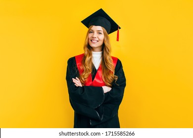 Happy attractive graduate in a master's dress, on a yellow background. Concept of the graduation ceremony