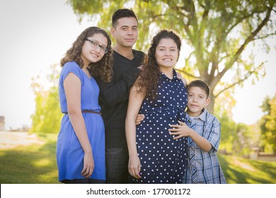 Happy Attractive Hispanic Family With Their Pregnant Mother Outdoors At the Park.