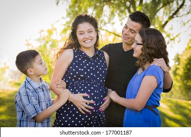Happy Attractive Hispanic Family With Their Pregnant Mother Outdoors At the Park.