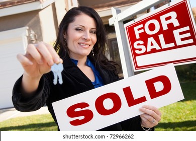 Happy Attractive Hispanic Woman Holding Sold Real Estate Sign and Keys in Front For Sale Real Estate Sign and House. - Powered by Shutterstock