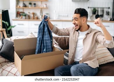Happy attractive indian or arabian guy opening big carton box, unpacking internet store order at home, contented with fast delivery service and the goods which received, smiling and feel satisfied