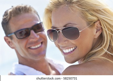 A Happy And Attractive Man And Woman Couple Wearing Sunglasses And Smiling In Sunshine At The Beach