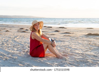 Happy attractive Mature woman in red dress enjoying outdoors and freedom on the beach, open arms outstretched in hope after coronavirus quarantine eased. Back to life, outdoors and new normal concept. - Powered by Shutterstock