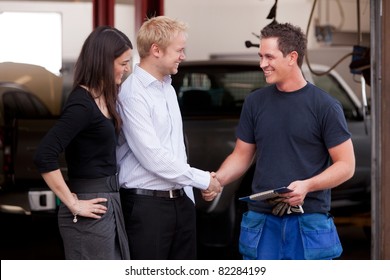 A Happy Attractive Mechanic Shaking Hands With A Customer Couple,happy With Their Service