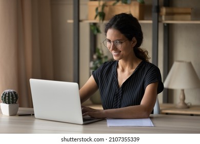 Happy attractive millennial hispanic latina businesswoman in eyeglasses working on computer in modern home office, communicating distantly with partner or colleague, consulting client remotely. - Shutterstock ID 2107355339