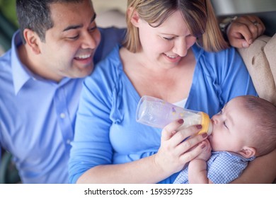 Happy Attractive Mixed Race Couple Bottle Feeding Their Son.