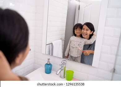 Happy Attractive Mom And Kid Brushing Their Teeth Together In Bathroom Sink In The Morning