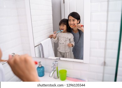 Happy Attractive Mom And Kid Brushing Their Teeth Together In Bathroom Sink In The Morning