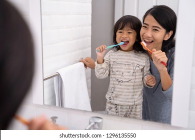 Happy Attractive Mom And Kid Brushing Their Teeth Together In Bathroom Sink In The Morning