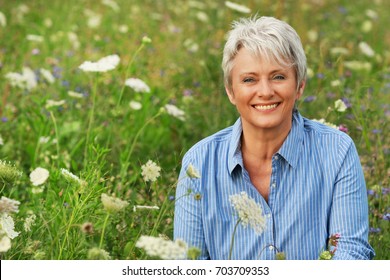 Happy attractive senior woman in a flower field in summer