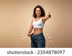 Happy attractive slender young middle eastern woman wearing huge jeans, showing thumb up, results of diet, white body shape lines around happy slim lady, collage for slimming concept, copy space