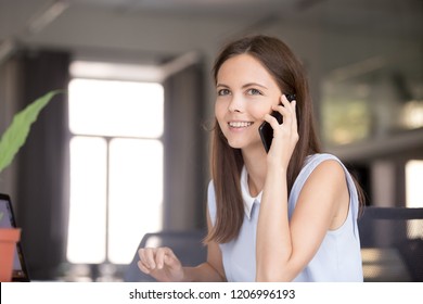 Happy Attractive Teen Girl Talking On The Phone Enjoying Pleasant Mobile Conversation, Smiling Millennial Woman Holding Cellphone Speaking Making Call Chatting By Smartphone Indoors