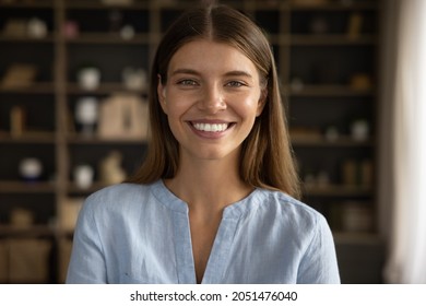 Happy attractive teen student girl home head shot portrait. Young millennial woman with natural makeup wearing pale linen shirt, smiling at camera, showing white perfect healthy teeth. Front view