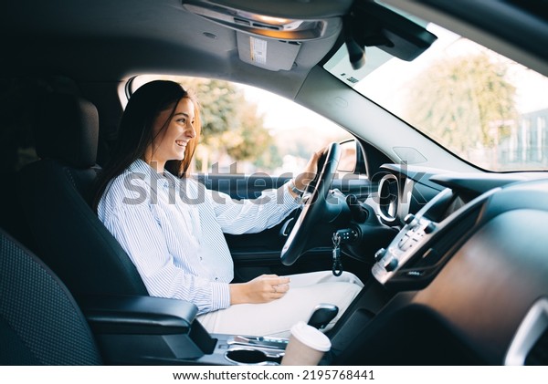 Happy attractive woman  has a joyful trip on car.\
Driver woman in luxury\
car