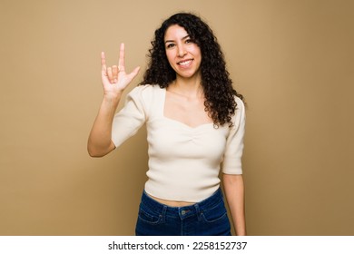 Happy attractive woman saying i love you using american sign language and smiling in front of a studio background - Powered by Shutterstock